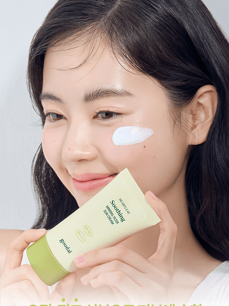 Model applying GOODAL Heartleaf Calming Mineral Filter Sun Cream on her face with a gentle smile.