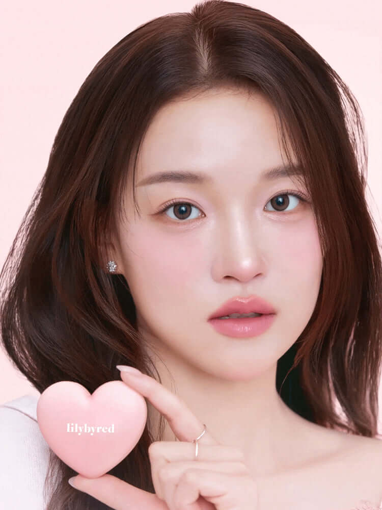 LILYBYRED Luv Beam Cheek 4.7g model holding a heart-shaped product, showcasing radiant makeup on a soft background.