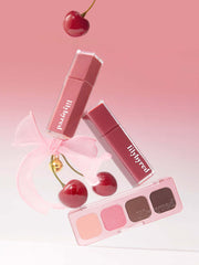 LILYBYRED Cherry Bell lip products and eyeshadow palette featuring cherry tones on a pink background.