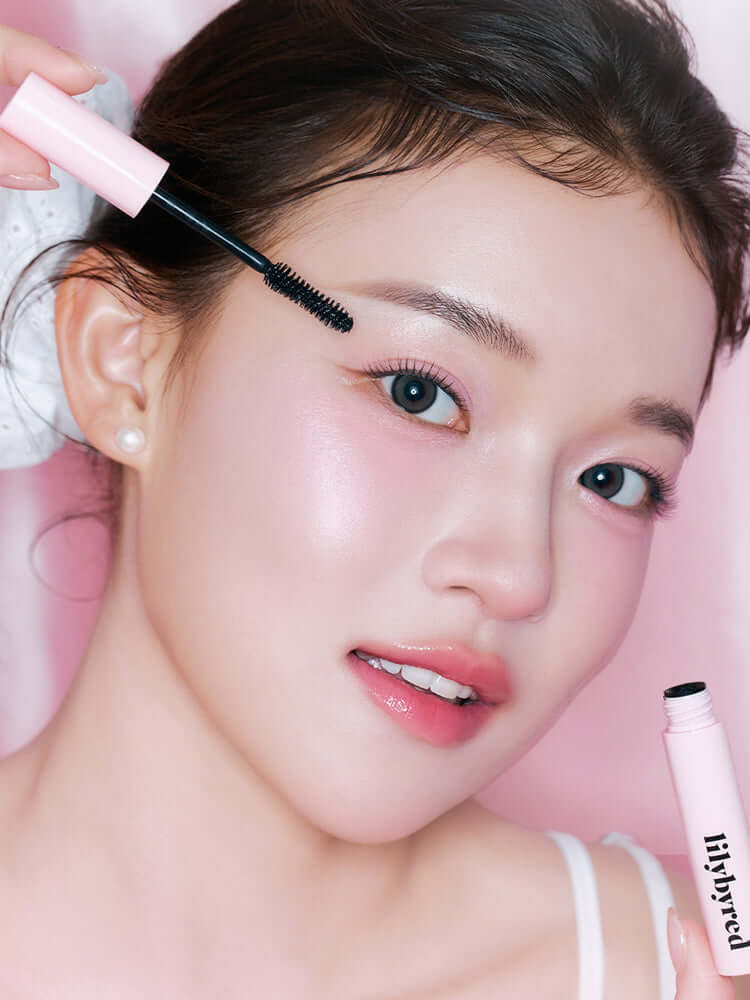 Model applying LILYBYRED Am9 To Pm9 Infinite Mascara 7g for defined lashes, showcasing beauty and natural makeup look.