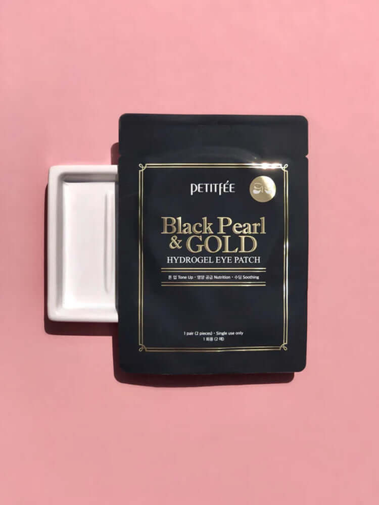 PETITFEE Black Pearl & Gold Hydrogel Eye Patch 1.4g (Single Use - 1 pair) packaging on a pink background.