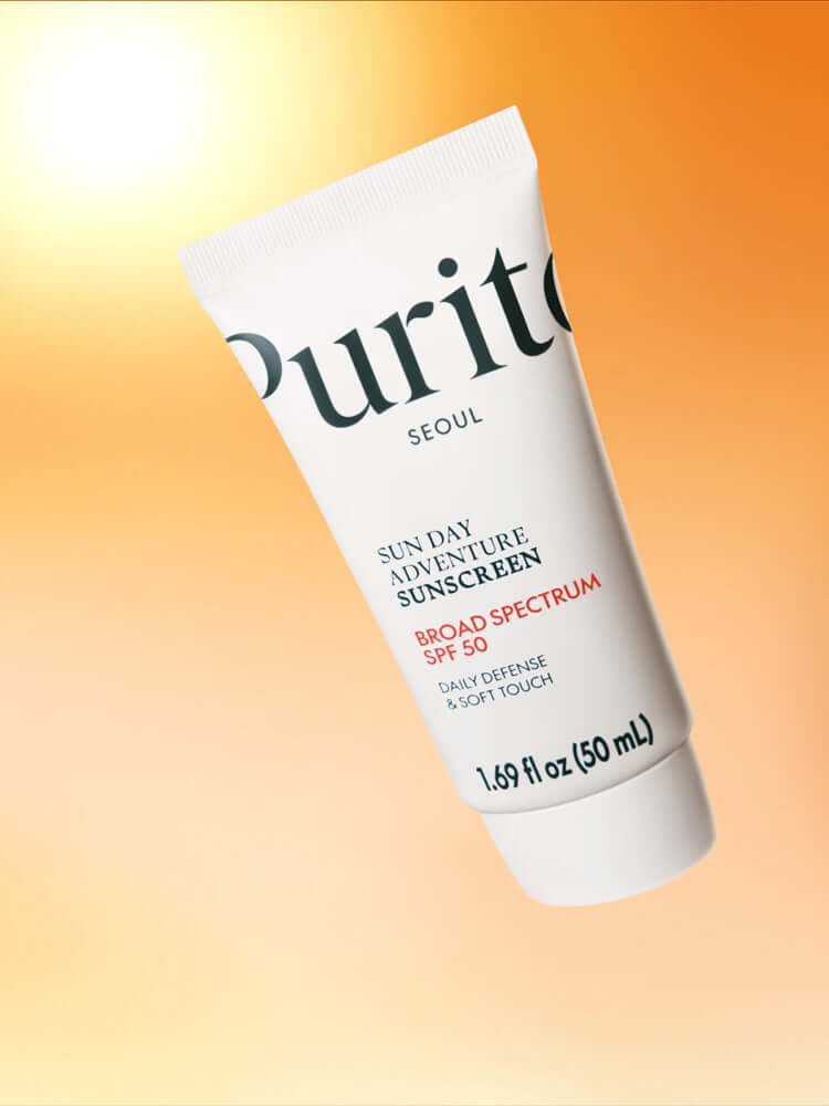 PURITO Sun Day Adventure Sunscreen 50ml tube with SPF 50, displayed against a warm orange background.