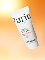 PURITO Sun Day Adventure Sunscreen 50ml tube with SPF 50, displayed against a warm orange background.