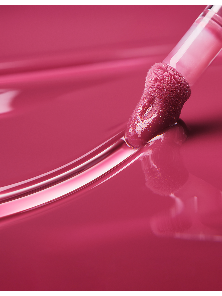 ROMAND Juicy Flash Lip Oil applicator dipped in glossy, pink lip oil showcasing its ultra-reflective shine.
