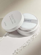 rom&nd Back Me No Sebum Powder 5g in a white container with a soft puff on a textured surface.
