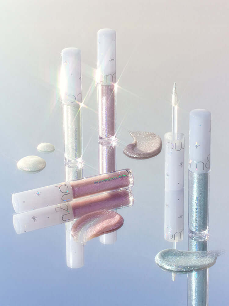 rom&nd Universe Liquid Glitter 2g collection with shimmering colors and glossy finishes on a reflective surface.