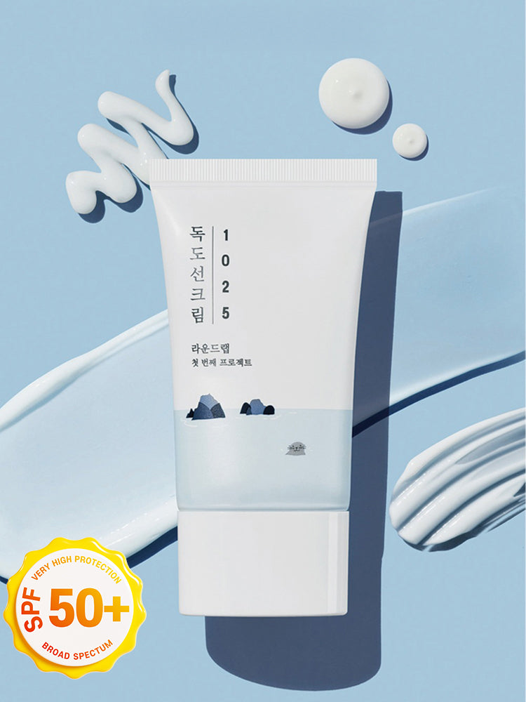 ROUND LAB 1025 Dokdo Sunscreen 50ml on a blue background with cream swirls