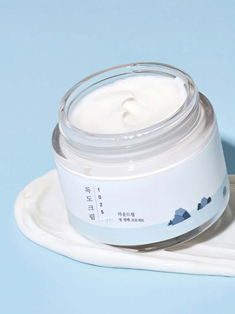 ROUND LAB 1025 Dokdo Light Cream 80ml in jar with a creamy texture on a blue background.
