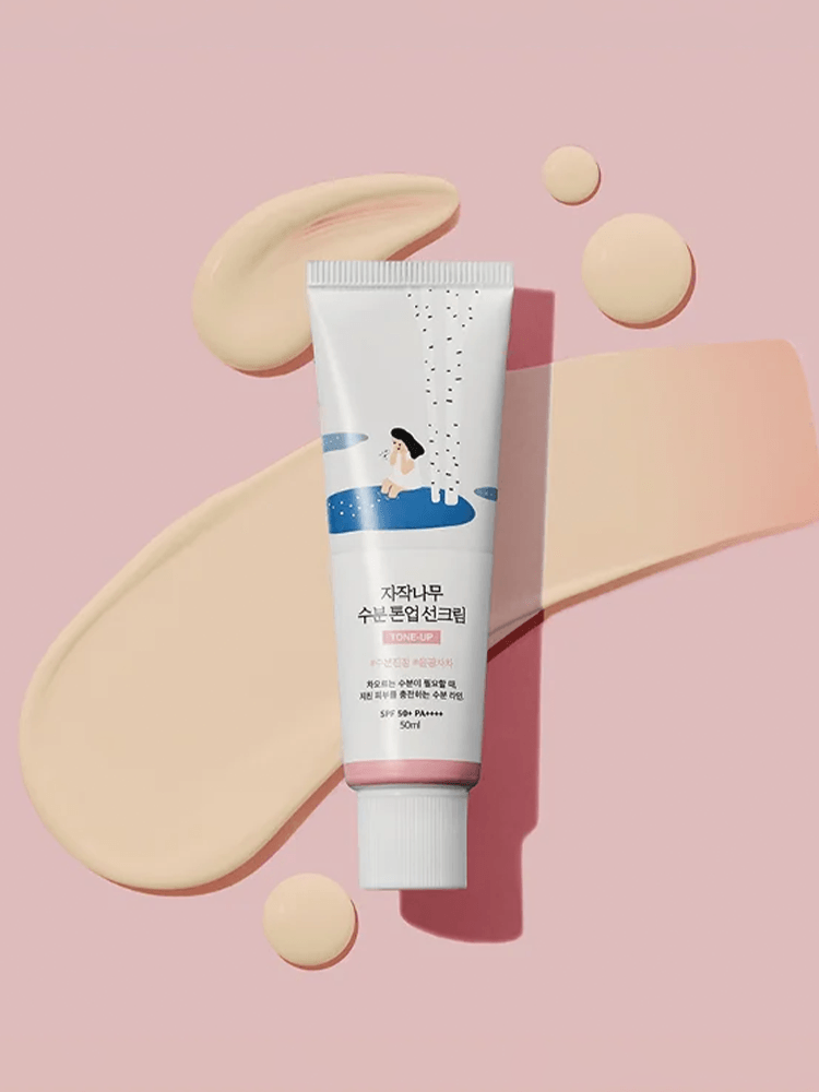 ROUND LAB Birch Juice Moisturizing Tone Up Sunscreen 50ml tube on pink background with cream swatches.