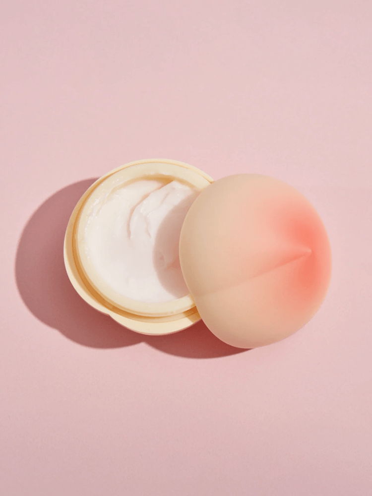 TONY MOLY Peach Hand Cream in a peach-shaped container, showcasing the creamy texture inside against a pink background.